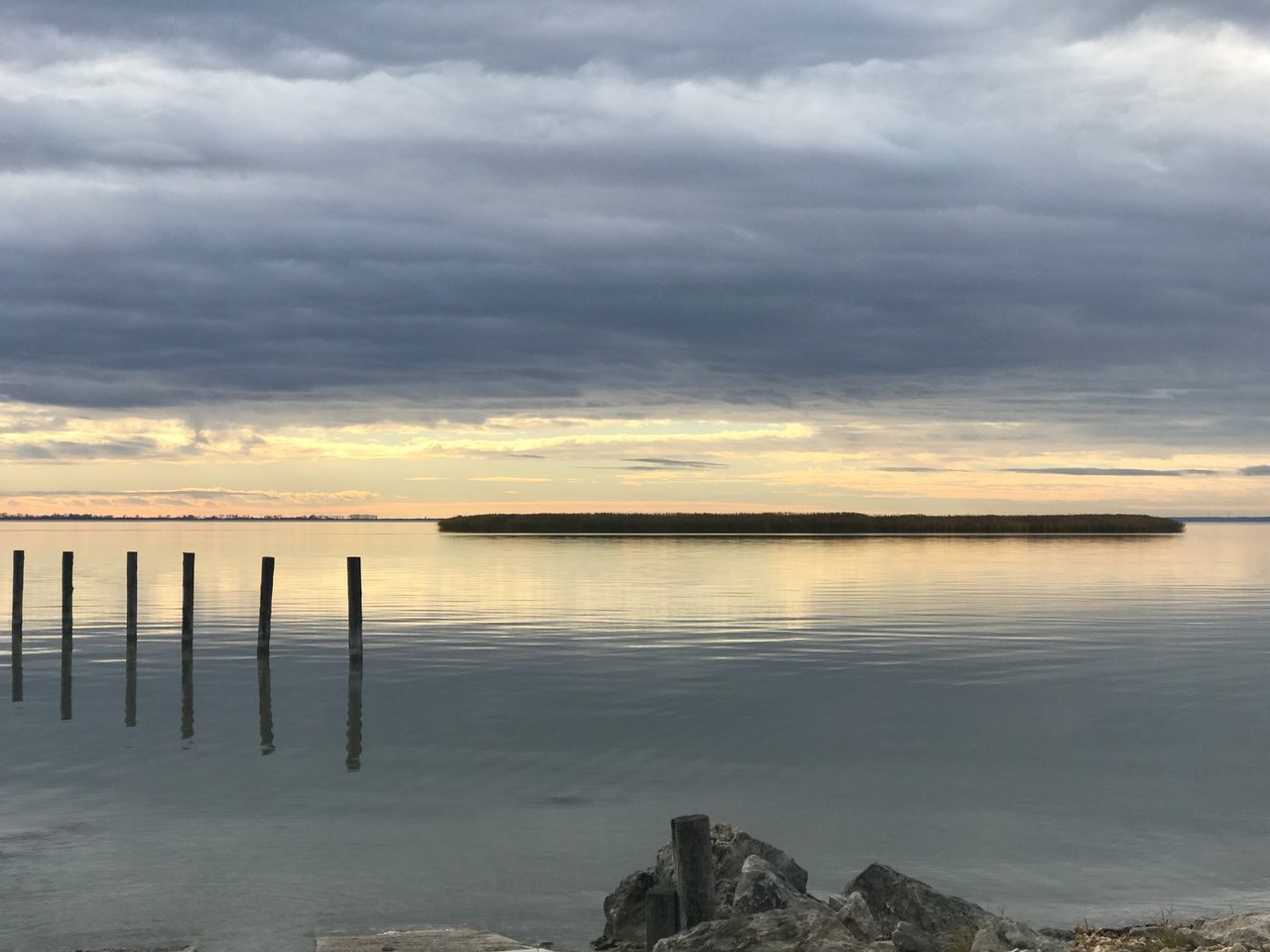 WOODEN POSTS IN SEA AGAINST SKY