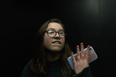 Young woman holding mobile phone while standing indoors