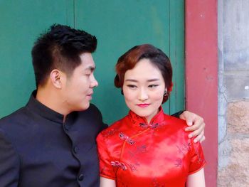 Young couple standing against red wall