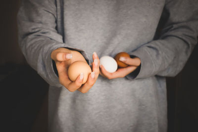 Midsection of girl holding eggs against black background