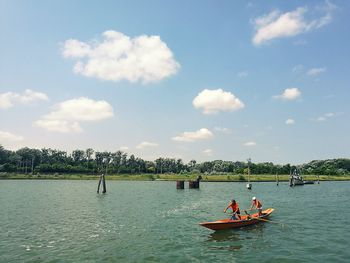 People on boat in river against sky