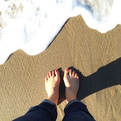 Low section of woman standing on sand at beach