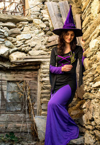 Smiling woman in costume standing against stone wall