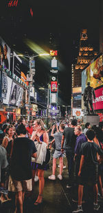 People walking on illuminated street in city at night