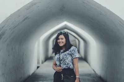 Portrait of young woman standing against wall