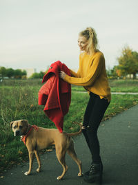 Full length of woman with dog standing outdoors