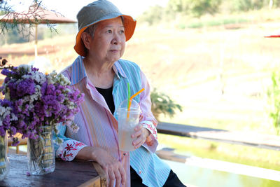 Senior woman holding drink while looking away