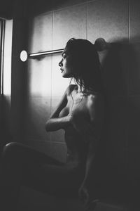Seductive woman sitting in bathroom at home