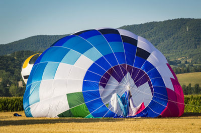 Multi colored hot air balloons on field against sky