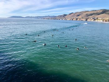 High angle view of people swimming in sea against sky