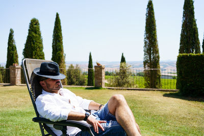 A man on vacation in tuscany sleeps in a lounger with a beautiful landscape in the background