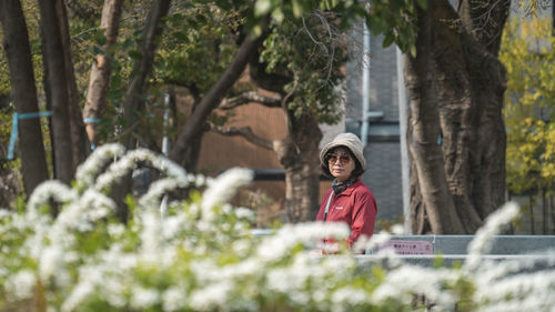 Side view of woman standing by plants in park