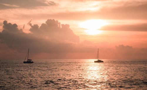 A sailboat playing in the sea at sunset