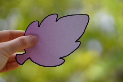 Close-up of hand holding heart shape leaf