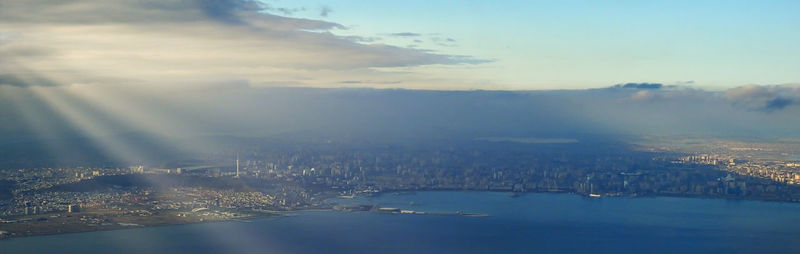 Aerial view of city by sea against sky