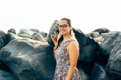 Young woman standing on rocks against clear sky