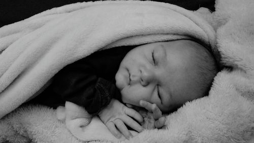 Close-up of baby boy covered with blanket while sleeping