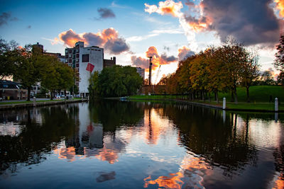 Reflection of trees and buildings in lake during sunset