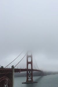 Suspension bridge over sea against clear sky