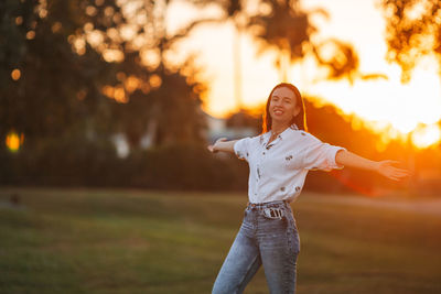 Portrait of young woman standing against trees at park
