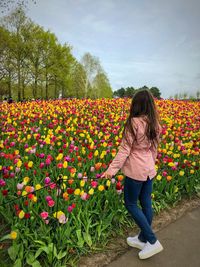 Full length of woman standing by flowering plants against sky