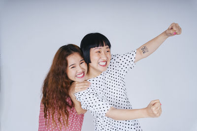 Portrait of happy lesbian couple against gray background