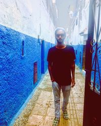 Portrait of young man standing against wall