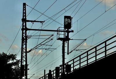 Low angle view of silhouette electricity pylon against sky