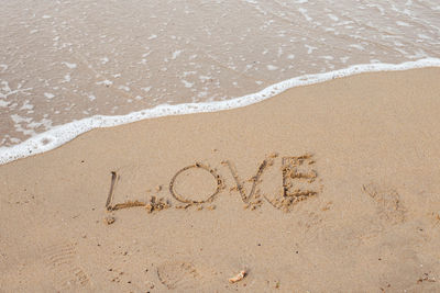 Love lettering on the sandy beach and sea water
