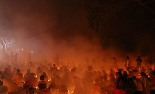 People are praying at rakher upobash under big tree in a smokey environment