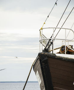 View of fishing boat in sea against cloudy sky