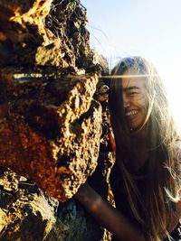 Portrait of smiling young woman against tree trunk