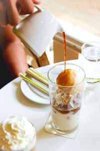 Midsection of person pouring coffee in cup on table