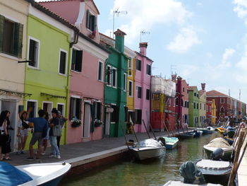 Boats moored in canal amidst buildings in city