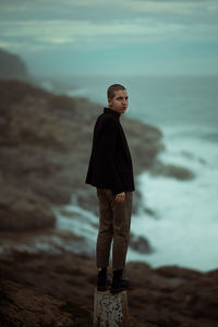 Portrait of young woman standing against sea