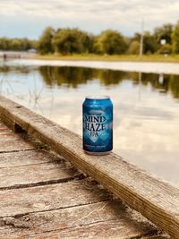 Close-up of text on wooden post against lake