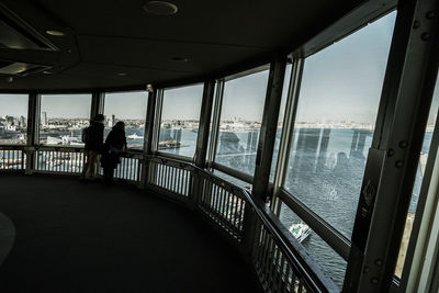 Silhouette man looking through window at sea