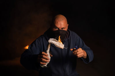 Portrait of young man holding molotov cocktail