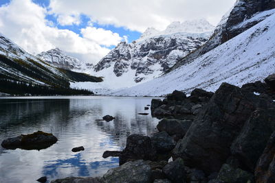 Scenic view of lake by snowcapped mountains against sky