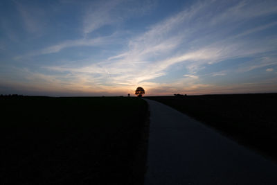 Silhouette tree on road against sky during sunset