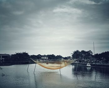 Boats moored by trees against sky