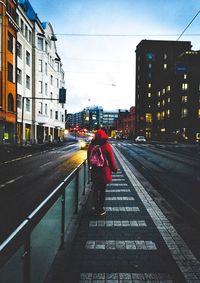 Rear view of woman walking on street amidst buildings in city