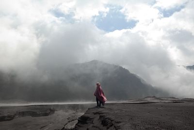 Girl wrapped in blanket standing against mountains during winter