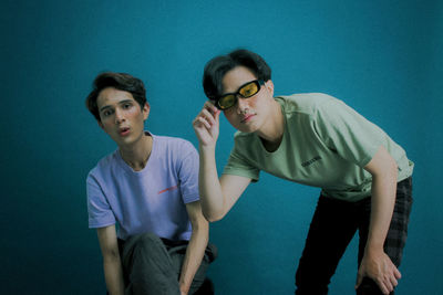 Portrait of young couple standing against blue background