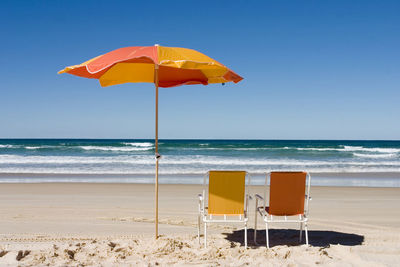 Deck chairs on beach against clear sky