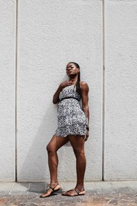 Full length portrait of woman standing against wall