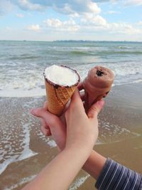 Midsection of woman holding ice cream on beach