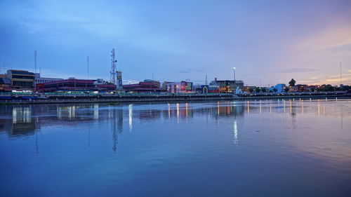 Reflection of illuminated buildings in city against sky