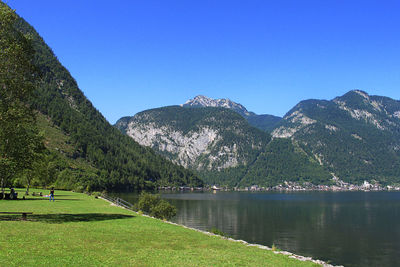 Scenic view of lake and mountains against clear blue sky