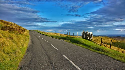 Road amidst field against sky